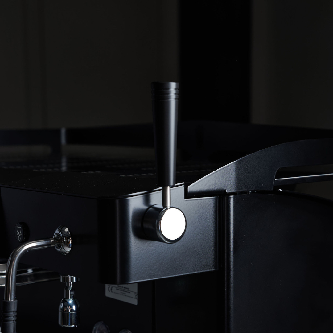 Close-up of a professional black espresso coffee machine with metal handle for the steamer.