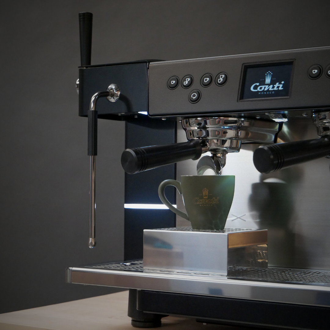 Close-up of the nGX serving coffee in a khaki cup, the screen displaying the CONTI logo.